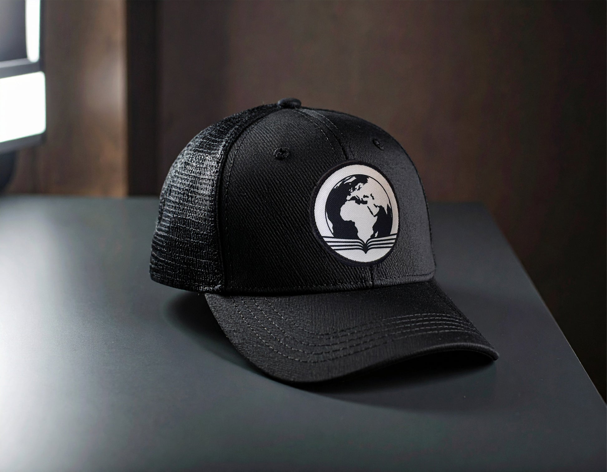 Black trucker cap with a white logo on a dark surface